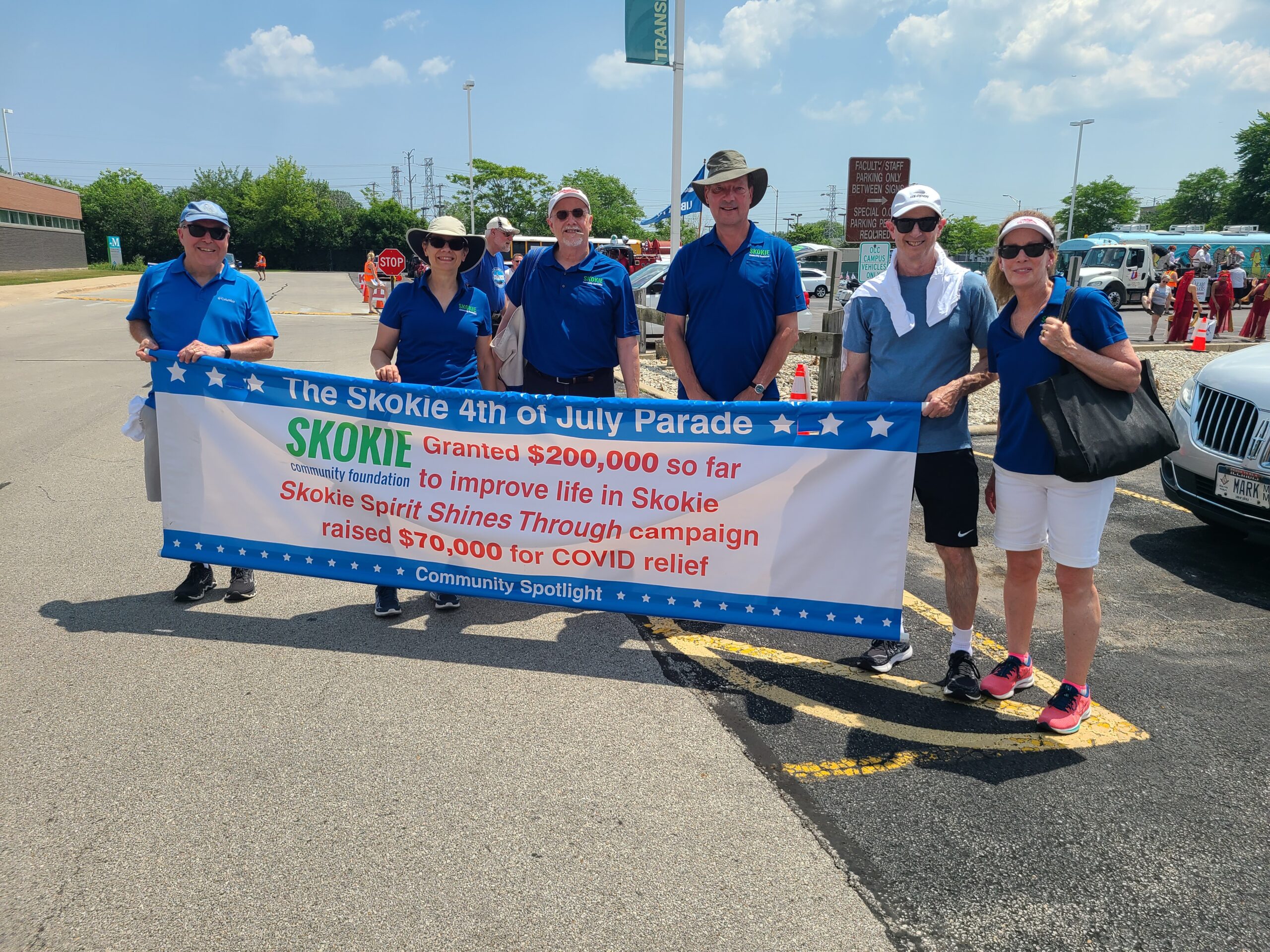 Skokie Community Foundation Board Members and supporters march behind the Skokie 4th of July "Community Spotlight" banner.